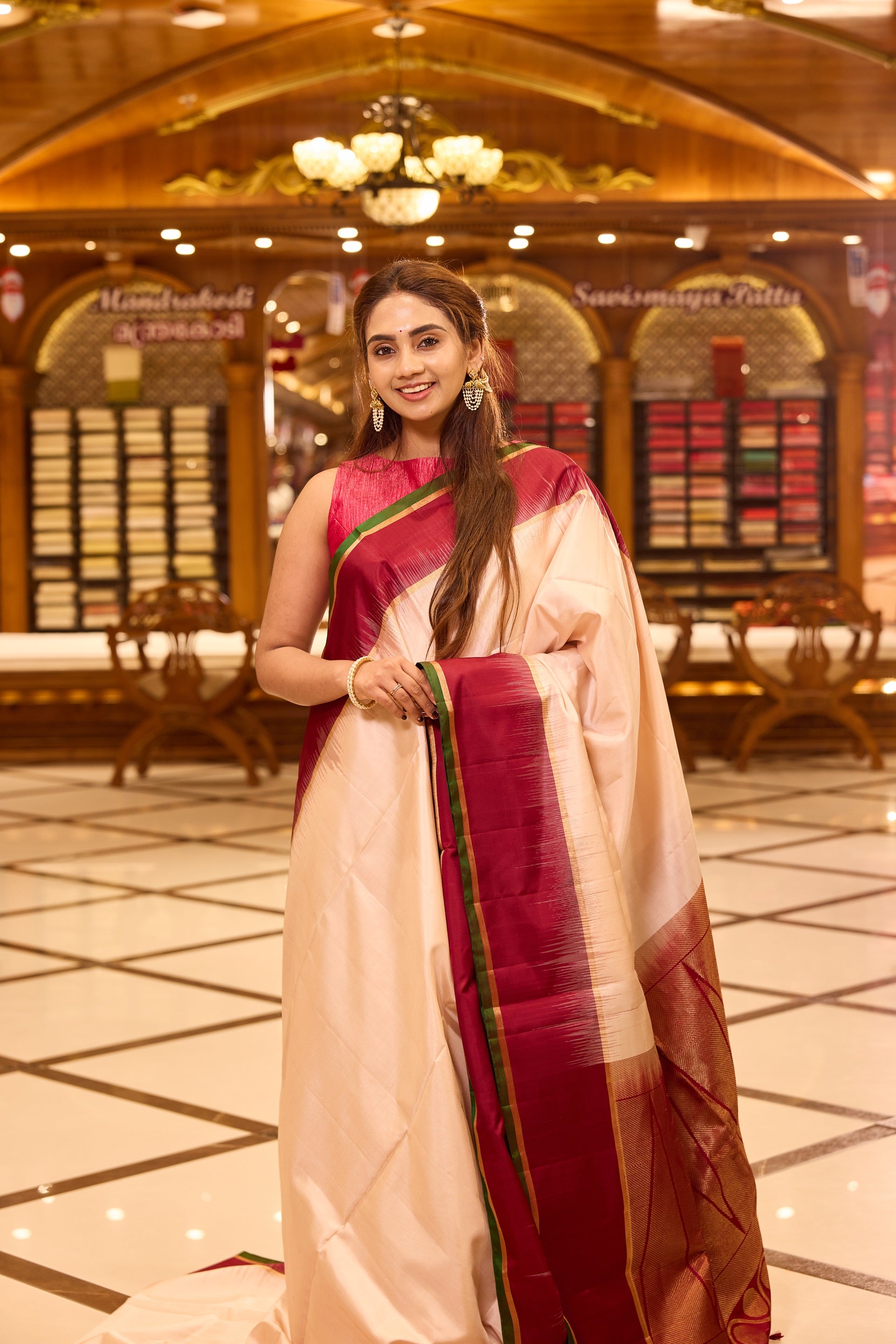 Ivory colour pure kancheepuram silk saree featuring a rich gold zari temple pallu, complemented with a contrast deep red border finished with gold and green selvedge and a matching deep red pallu, beautifully paired with a matching blouse.