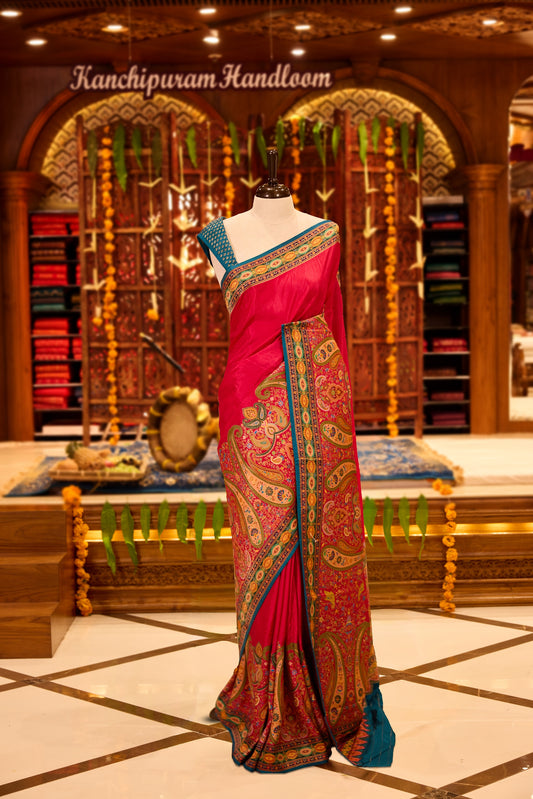 Magenta colour Pashmina silk saree beautifully woven with intricate paisley and floral motifs in vibrant multicolour weaves, framed by teal and gold ornamental borders and an elaborate artistic pallu, paired with a coordinated woven blouse piece.