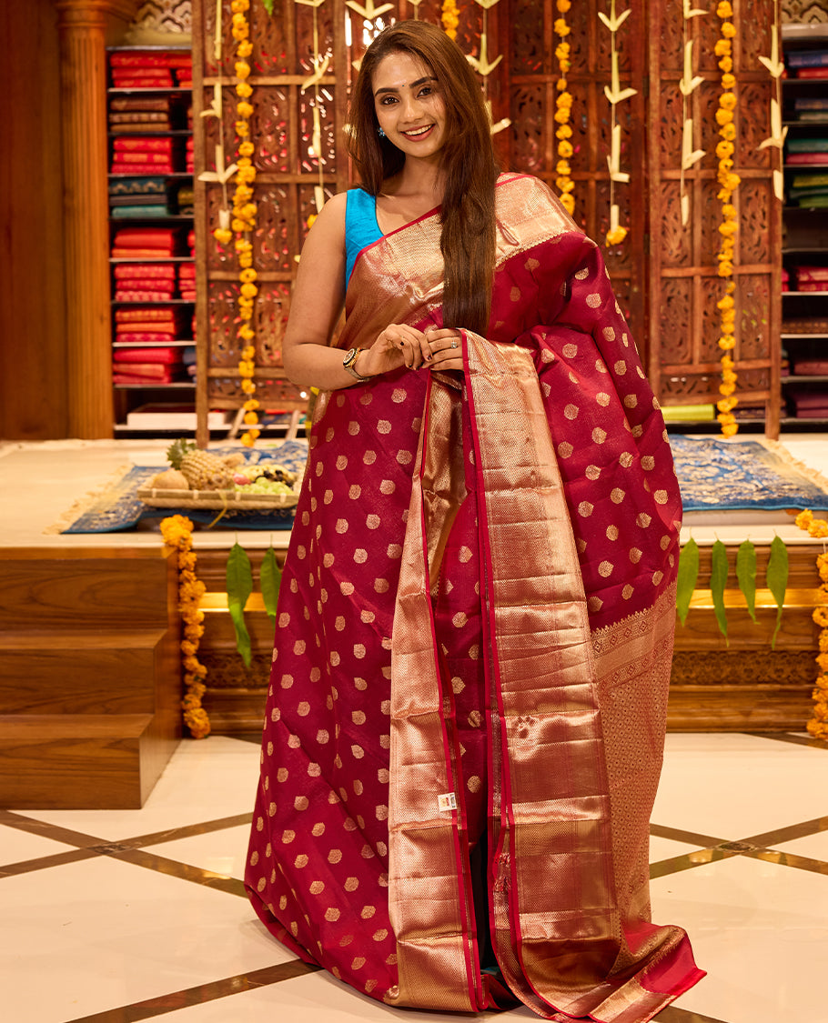 Wine colour Kancheepuram silk saree with classic gold zari polka motifs all over, complemented by a lustrous gold zari border and pallu, and paired with a matching blouse.