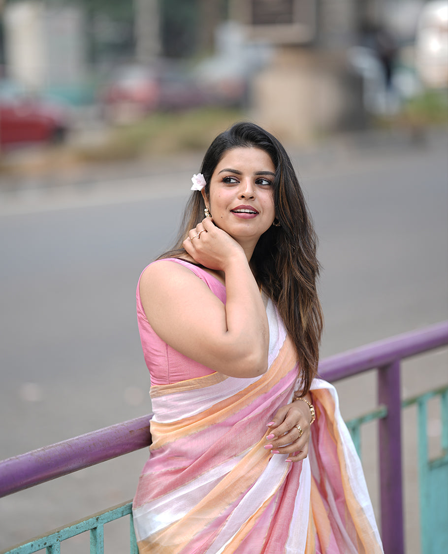 Pastel pink, yellow & white mul mul cotton saree accentuated by delicate gold borders and a subtle striped body, paired with a matching blouse piece.