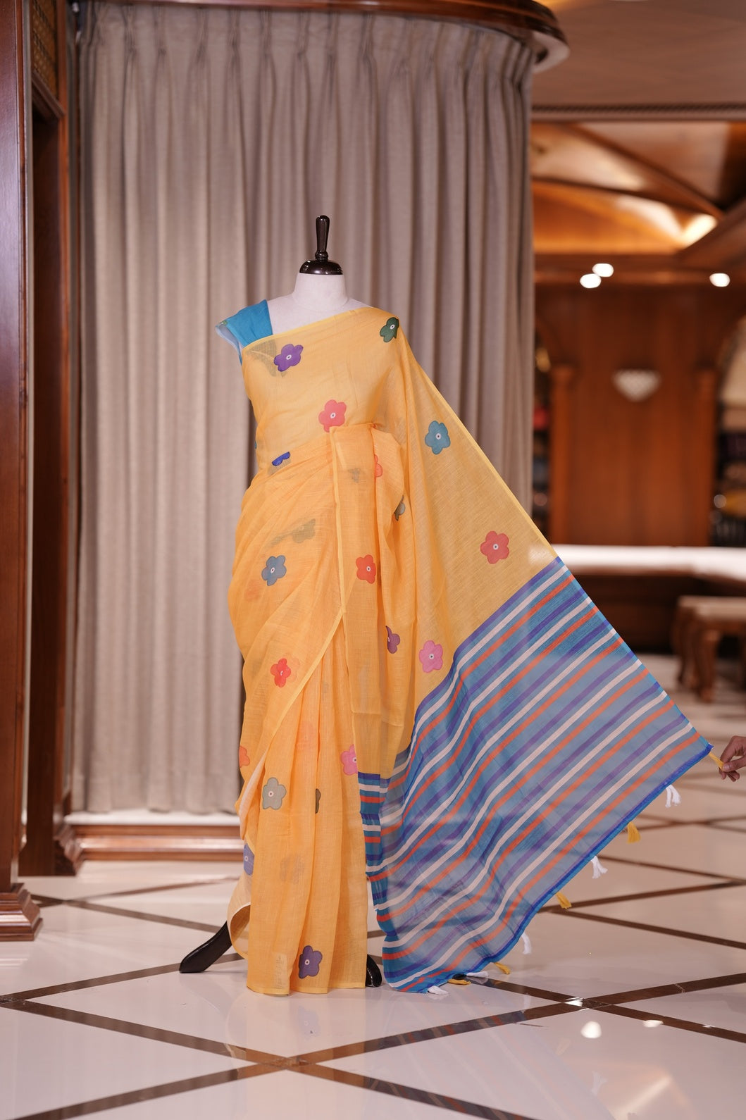Yellow colour Soft linen saree adorned with multiple floral digital prints all over, complemented by a contrast striped pallu & Paired with a beautifully contrasted printed blouse piece for an elegant contemporary look.