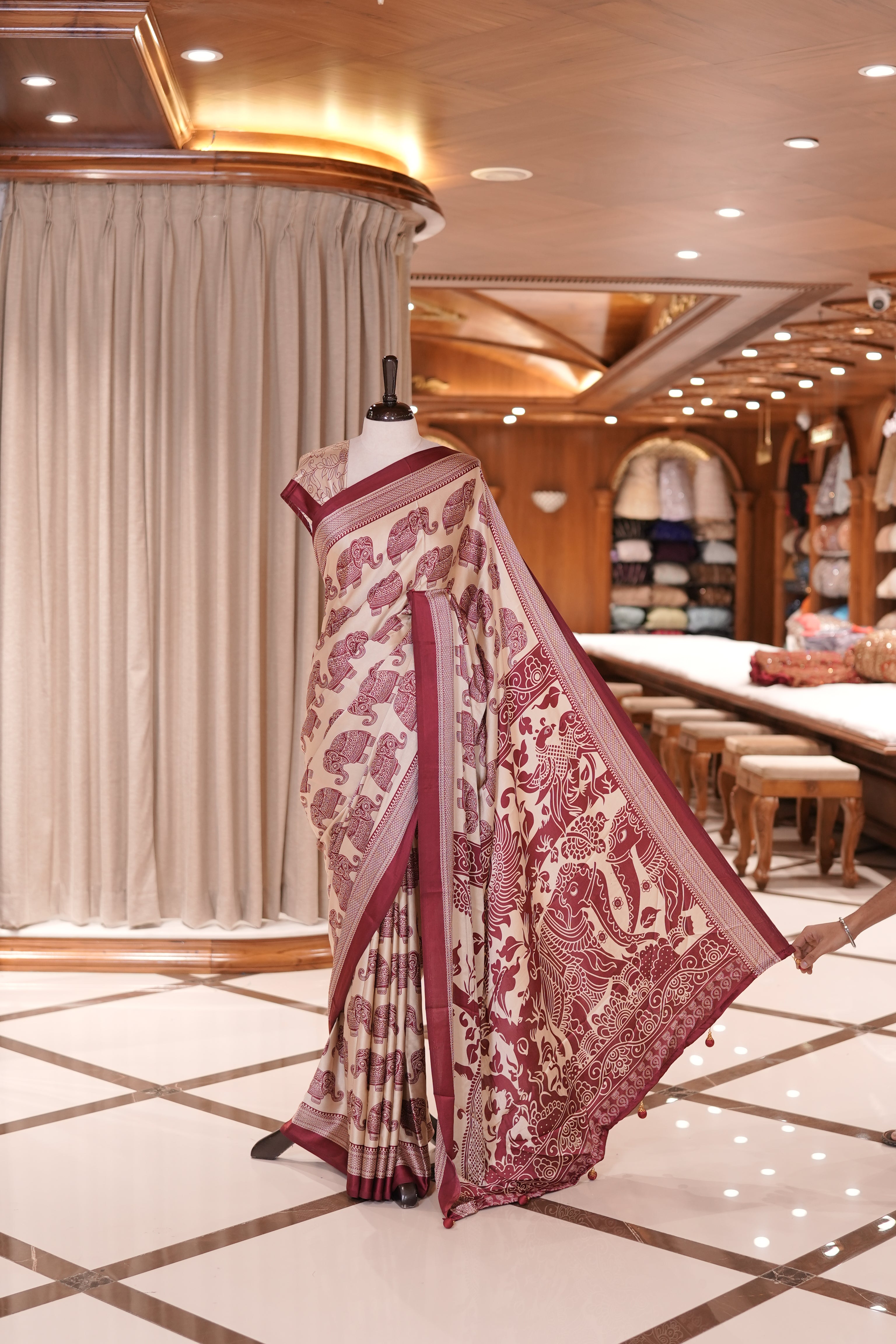 Cream and maroon satin modal saree featuring intricate elephant motifs and an artistic pallu, paired with a matching blouse