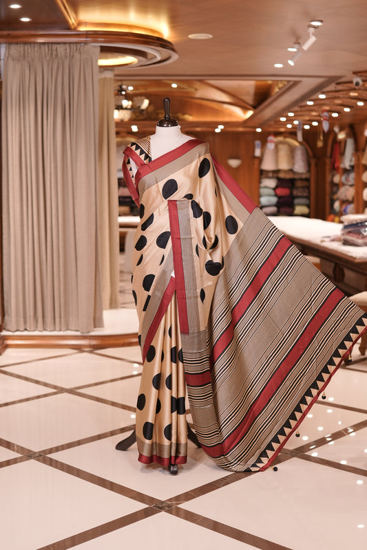 Cream colour semi modal saree featuring bold black polka dots and elegant striped detailing, finished with a contrasting maroon border and paired with a perfectly matching blouse