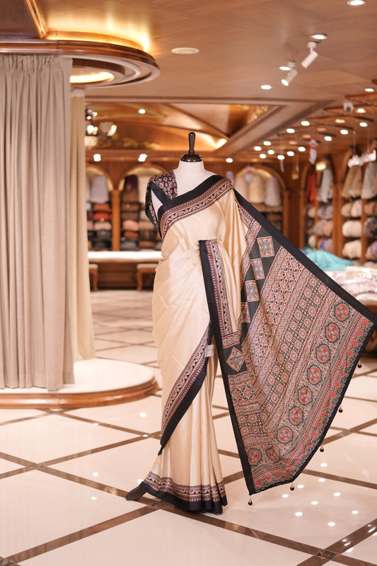 Cream colour semi modal saree featuring an elegant Black border with intricate woven designs and a richly detailed pallu, paired with a matching blouse