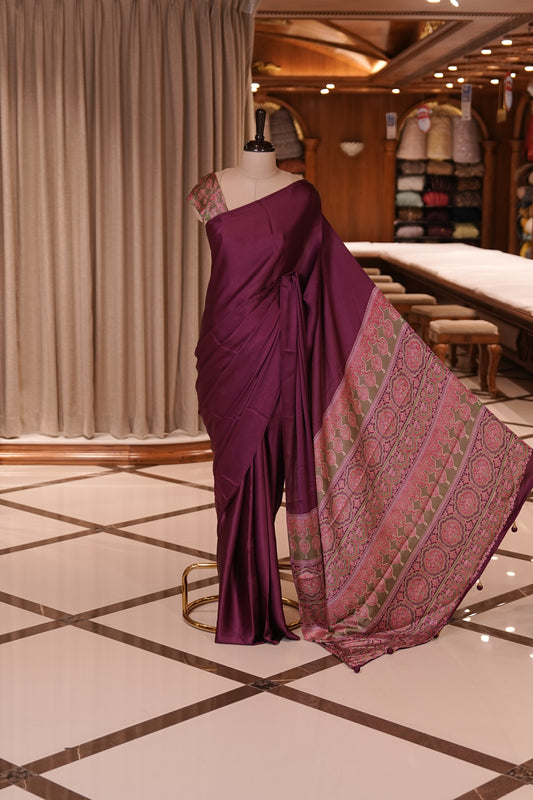 Wine Colour semi modal saree featuring a graceful solid body, beautifully enhanced with an intricately woven contrast Ajrakh printed pallu and a perfectly matching Ajrakh blouse.
