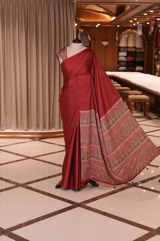 Maroon Colour semi modal saree featuring a graceful solid body, beautifully enhanced with an intricately woven contrast Ajrakh printed pallu and a perfectly matching Ajrakh blouse.