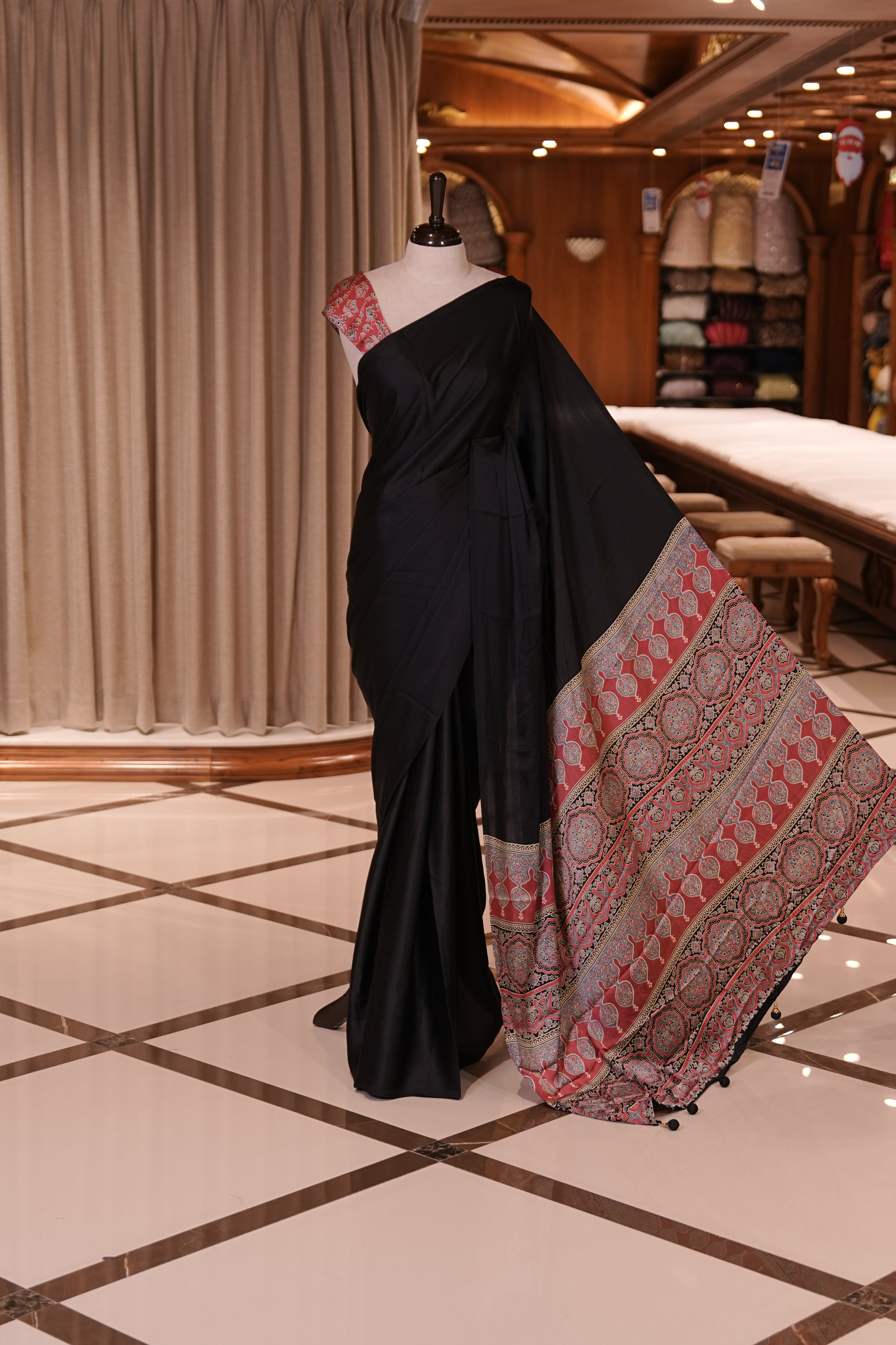Black Colour semi modal saree featuring a graceful solid body, beautifully enhanced with an intricately woven contrast Ajrakh printed pallu and a perfectly matching Ajrakh blouse.