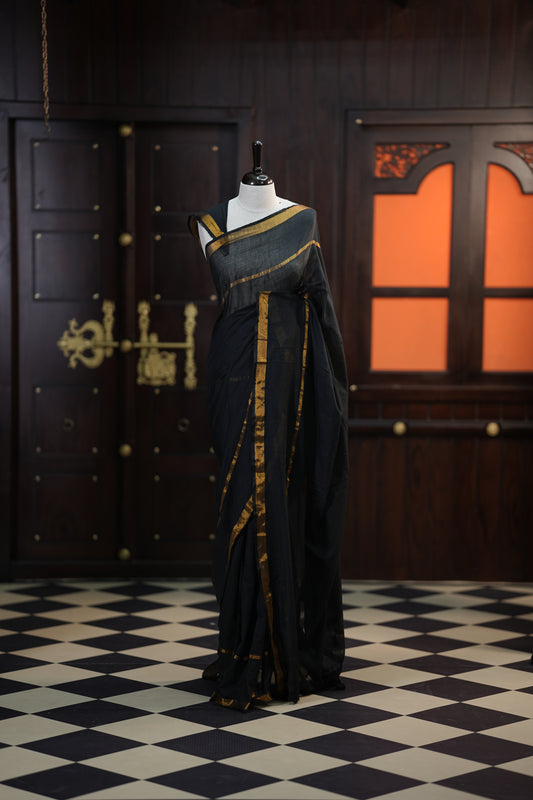 Black colour mul mul cotton saree accentuated by delicate Gold borders and body, paired with a matching blouse.