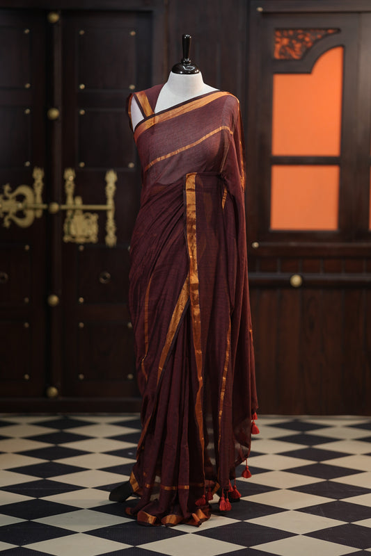 Maroon colour mul mul cotton saree accentuated by delicate Gold borders and body, paired with a matching blouse.