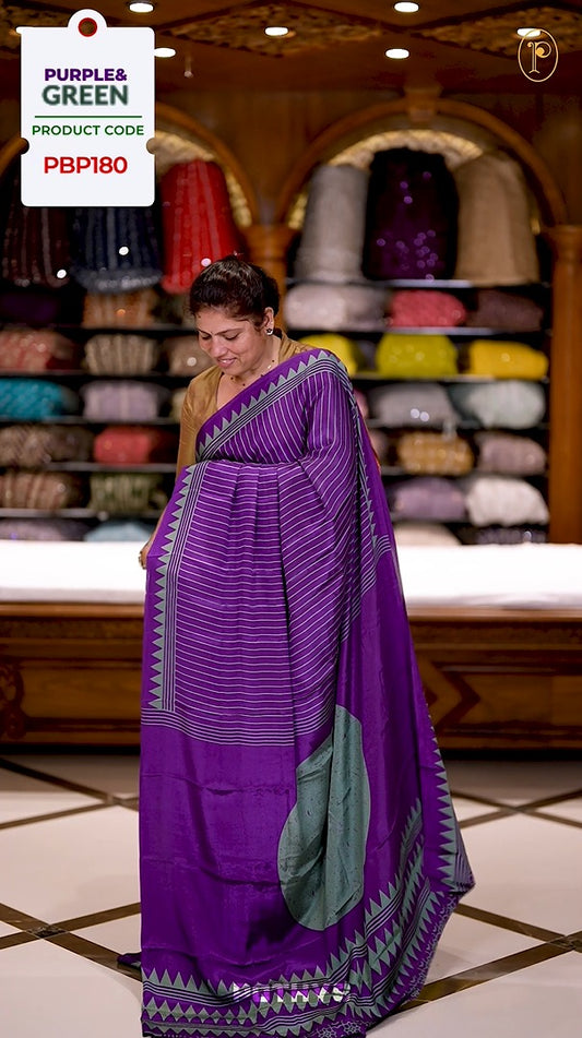 Purple and Green colour semi modal saree featuring a vertical line prints, accented with a contrasting temple border and a bold circular motif on the pallu, paired with a matching printed blouse.