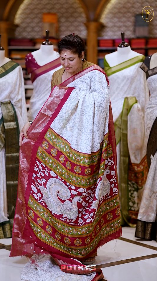 White colour Kalamkari saree featuring intricate prints, paired with a striking red and golden traditional border & The multicolor Kalamkari printed pallu adds vibrant charm, perfectly matched with a coordinating blouse.