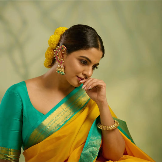 Sunshine yellow colour Kanchipuram Silk saree, featuring intricate gold motifs, a vibrant teal green border, and a grand pallu paired with a matching blouse