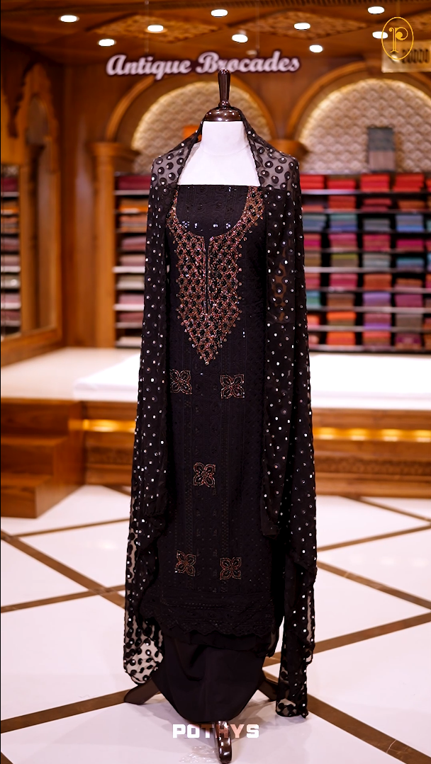Black colour georgette partywear churidhar material featuring intricate stone and beadwork on the top, paired with a plain bottom and a mirror worked dupatta.