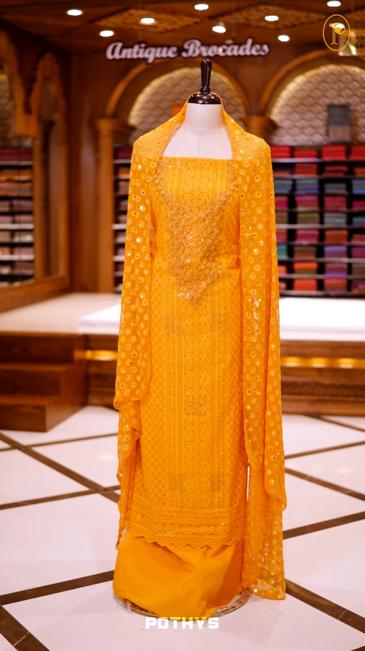 Yellow colour georgette partywear churidhar material featuring intricate stone and beadwork on the top, paired with a plain bottom and a mirror worked dupatta.