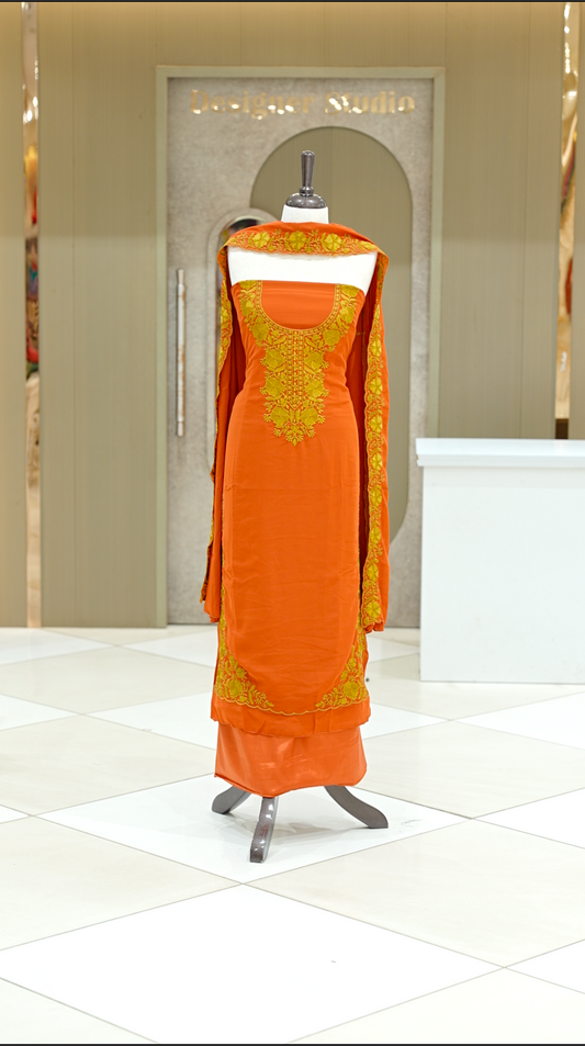 Orange colour georgette salwar suit material featuring intricate Mustard Yellow floral thread embroidery on the neckline and side opening, complemented with a matching bottom and dupatta. Comes with lining included for added comfort and finish.