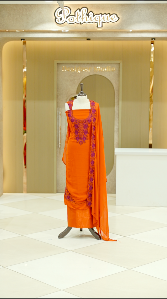 Orange colour georgette salwar suit material featuring intricate Maroon floral thread embroidery on the neckline and side opening, complemented with a matching bottom and dupatta. Comes with lining included for added comfort and finish.