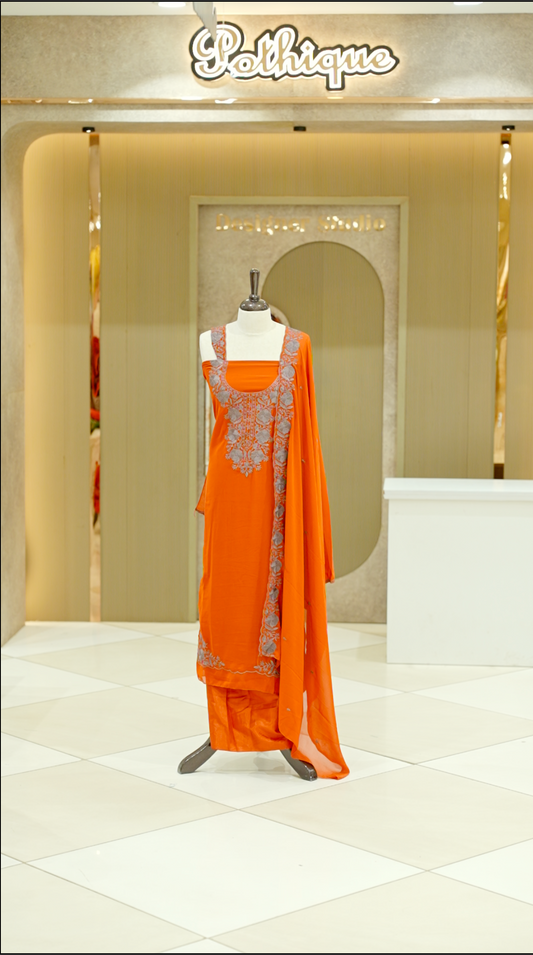 Orange colour georgette salwar suit material featuring intricate Grey floral thread embroidery on the neckline and side opening, complemented with a matching bottom and dupatta. Comes with lining included for added comfort and finish.