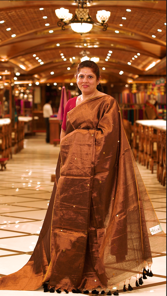 Brown colour Semi Tissue saree featuring a plain body adorned with delicate sequin detailing throughout, crafted in a borderless design. Comes without a blouse piece.