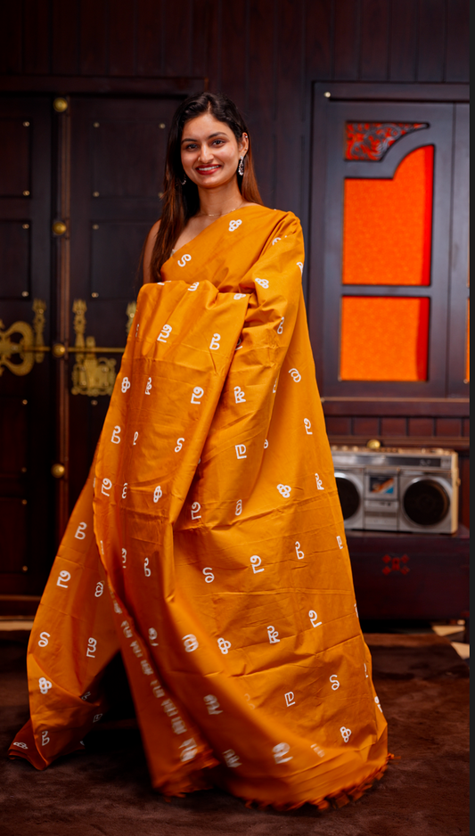Mustard Yellow colour Poly cotton saree featuring Malayalam Letters Print on body, pallu with tassels, Contrast Colour Blouse piece.