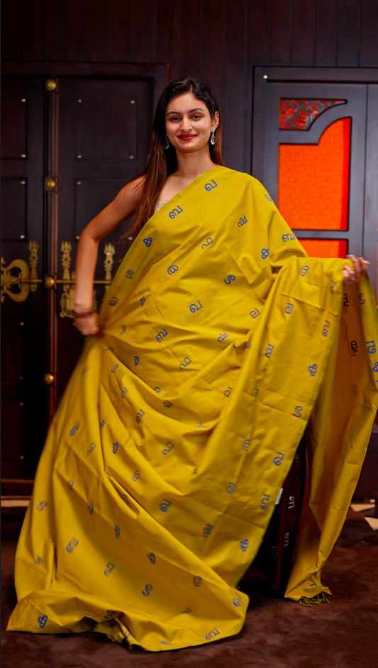 Olive Yellow colour Poly cotton saree featuring Malayalam Letters Print on body, pallu with tassels, Contrast Colour Blouse piece.