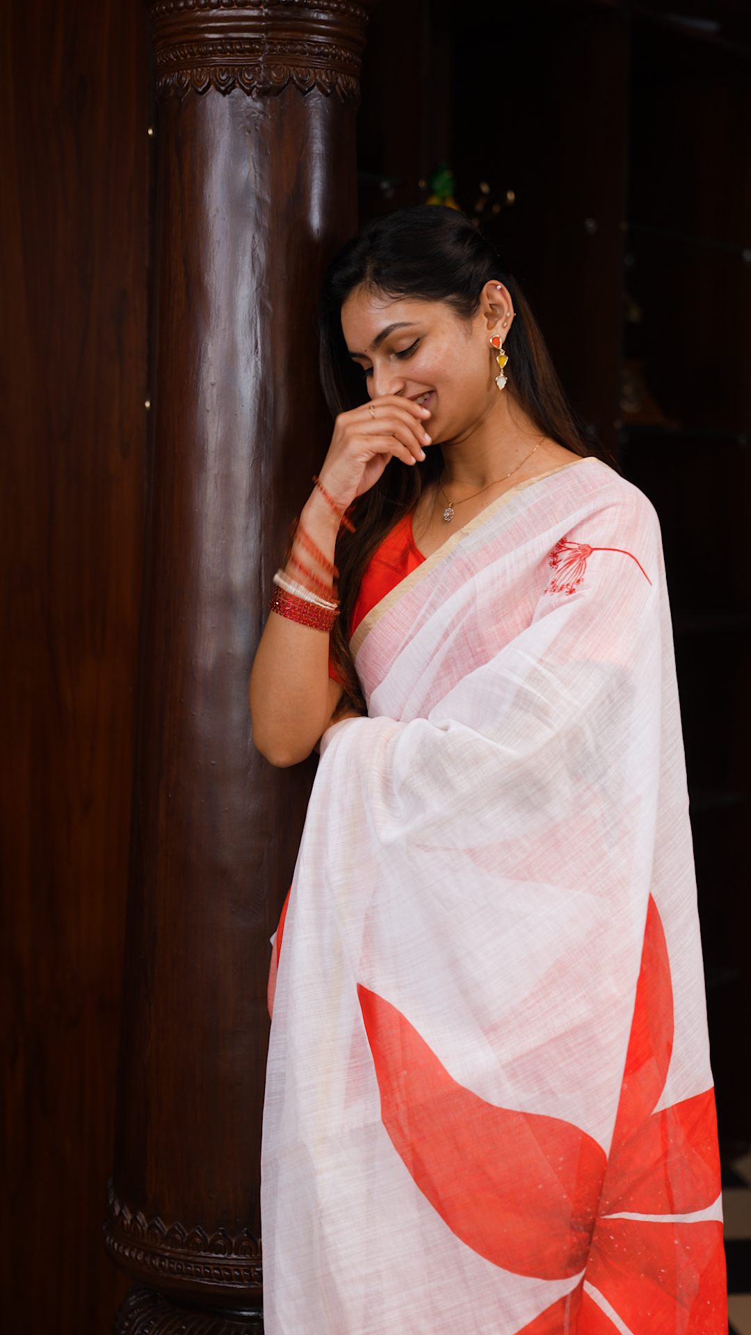 White colour linen saree featuring Red colour small floral print on body, complemented by contrast Colour border, big floral print & tassels on pallu, comes with contrast colour blouse piece.