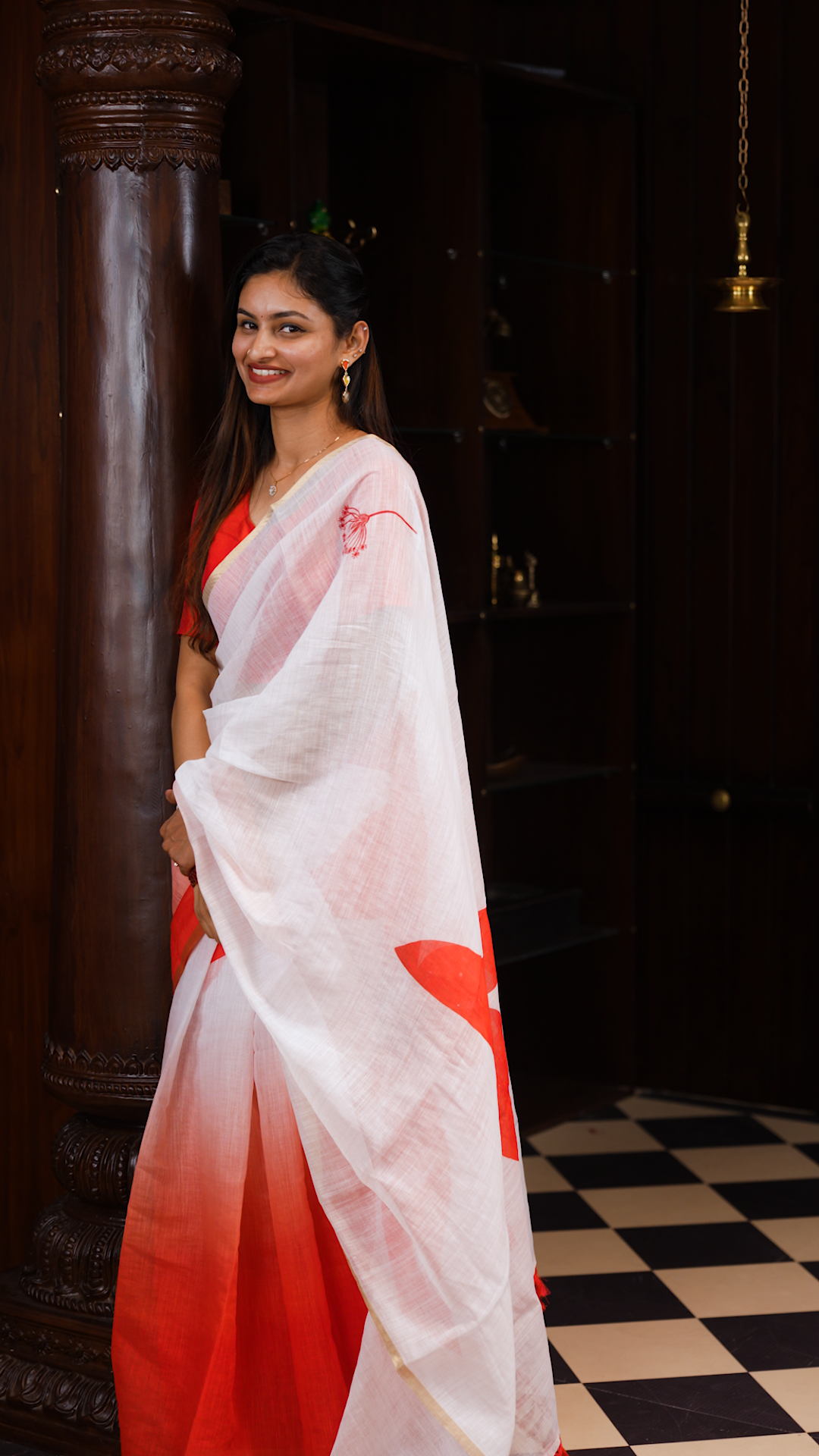 White colour linen saree featuring Red colour small floral print on body, complemented by contrast Colour border, big floral print & tassels on pallu, comes with contrast colour blouse piece.