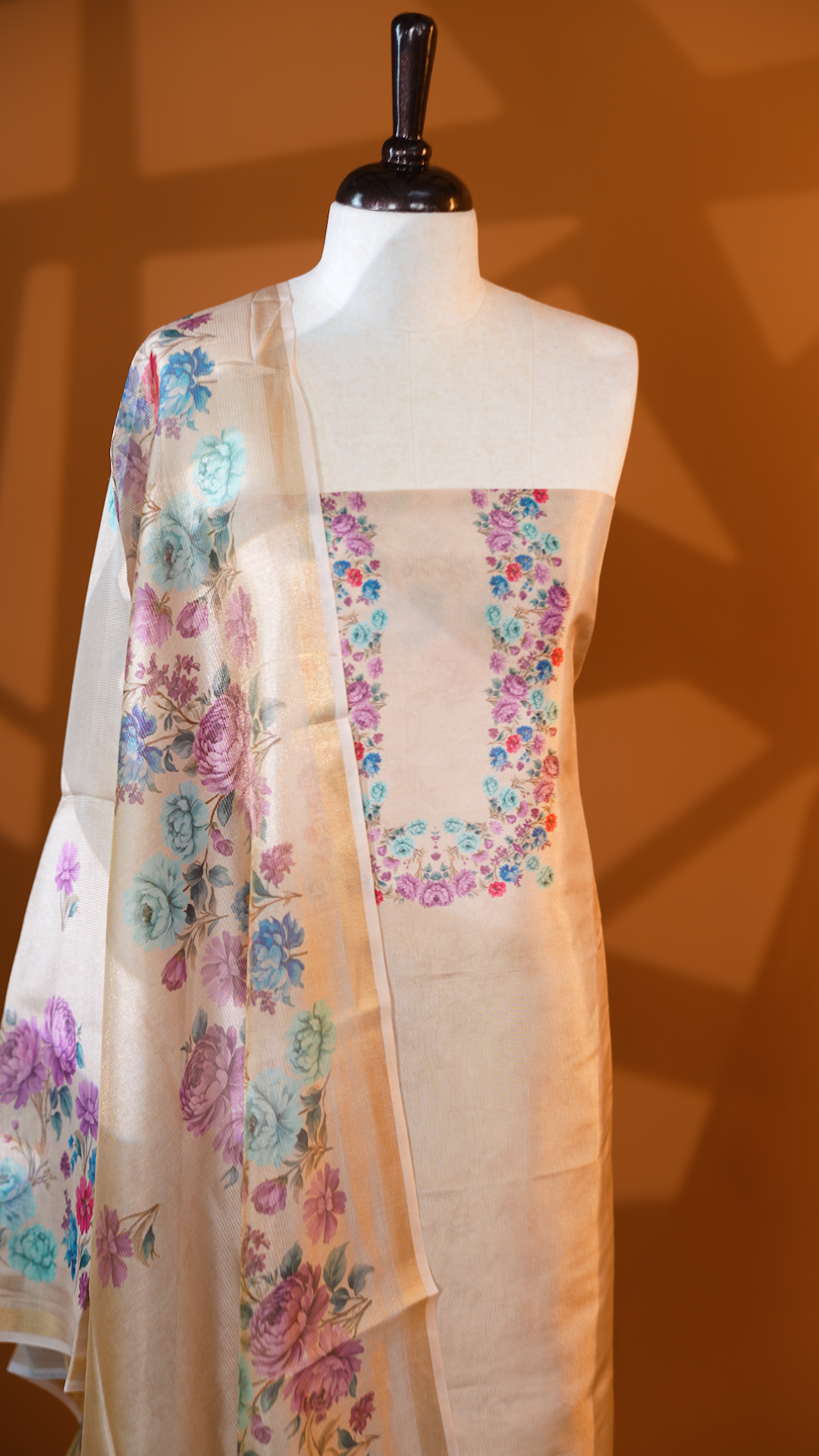 Light gold colour Tissue Salwar material featuring Pink & Blue colour floral print, paired with Dupatta with same print & Golden line detailed border and santoon bottom material.