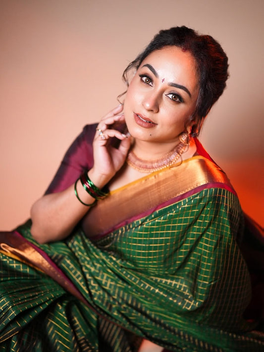 Bottle green and maroon Kancheepuram silk saree adorned with zari checks on the body, traditional bavanji border, mustard-maroon edge piping, and a contrasting jacquard zari pallu, paired with a matching maroon blouse