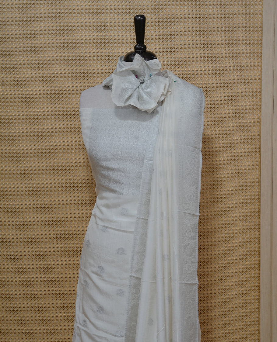 Cream colour Salwar material featuring silver zari Buttas on body & zari worked Neck Portion, paired with matching dupatta & Bottom.
