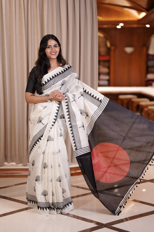 White colour semi khadi saree adorned with black floral motifs and a striking red circle pallu, exuding timeless elegance and contemporary charm & Comes with a matching blouse piece.