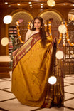 Pure silk saree featuring a mustard yellow body adorned with small zari and thread motifs, complemented by a rich maroon zari woven border and grand pallu.