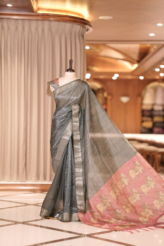 Grey & red colour Dolla silk saree featuring a striped body with a matching golden zari border, The pallu showcases exquisite Kalamkari prints, complemented by a contrast printed blouse.