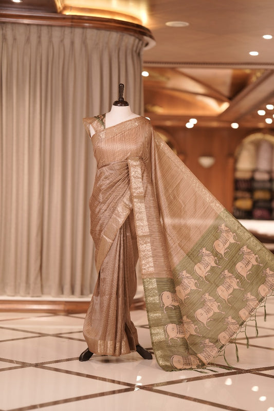 Chikku & green colour Dolla silk saree featuring a striped body with a matching golden zari border, The pallu showcases exquisite Kalamkari prints, complemented by a contrast printed blouse.