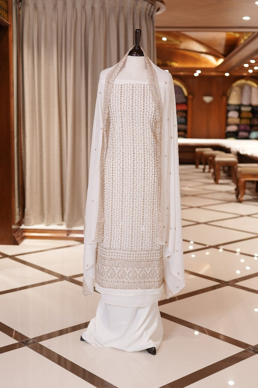 White Colour Georgette top adorned with gold zari and sequin work, paired with a scallop bordered dupatta featuring golden zari embroidery and a plain bottom.