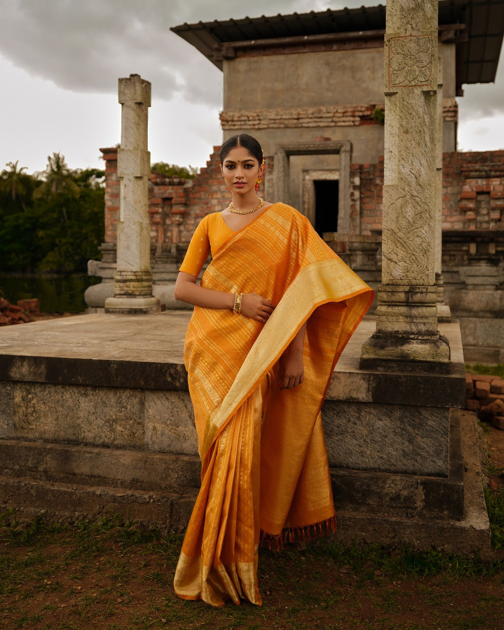 Golden mustard colour Samudrika wedding saree featuring elegant vertical geometric jacquard designs woven in antique silver and copper zari, complemented by a traditional zari pettu border and paired with a matching blouse piece.