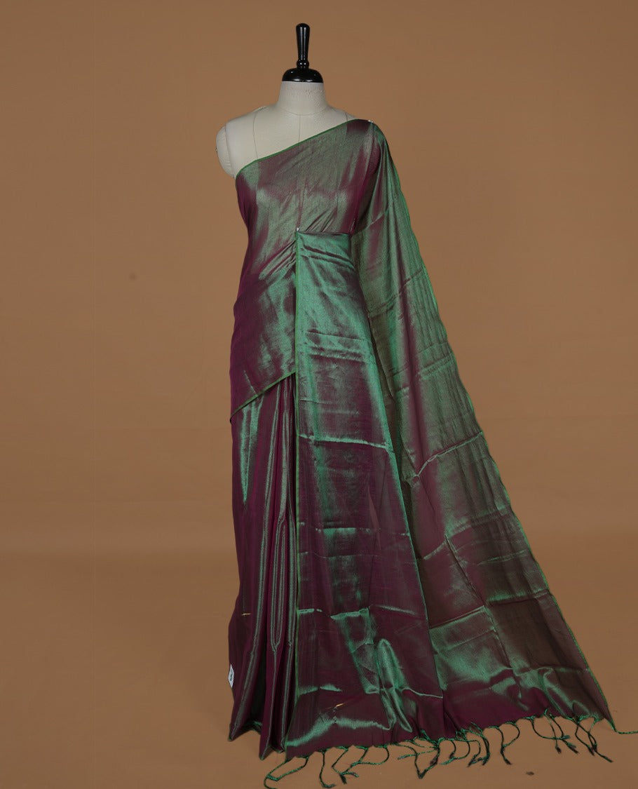 Green & red double shade colour semi tissue saree featuring an elegant plain body, designed without a border and comes without a blouse piece.