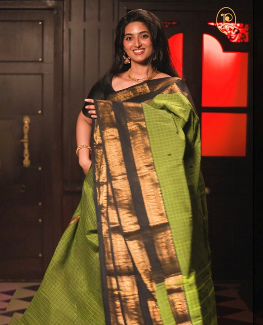 Green colour chettinad cotton saree Highlighting Gold zari striped body, contrast black colour traditional border, paired with matching blouse piece.