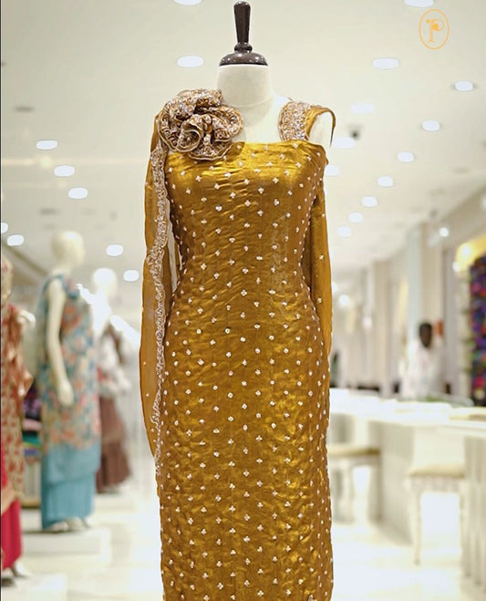 Yellow colour Fenty silk salwar material highlighting gold sequins on body and scalp design on border, matching dupatta with scalp design, paired with matching bottom.