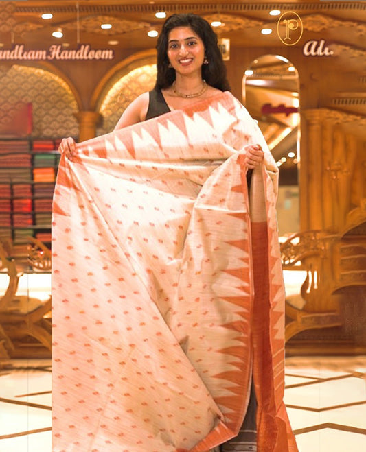 Cream colour Semi Jute saree featuring thread motifs across the body with a rust orange colour traditional temple border, paired with a running blouse piece.