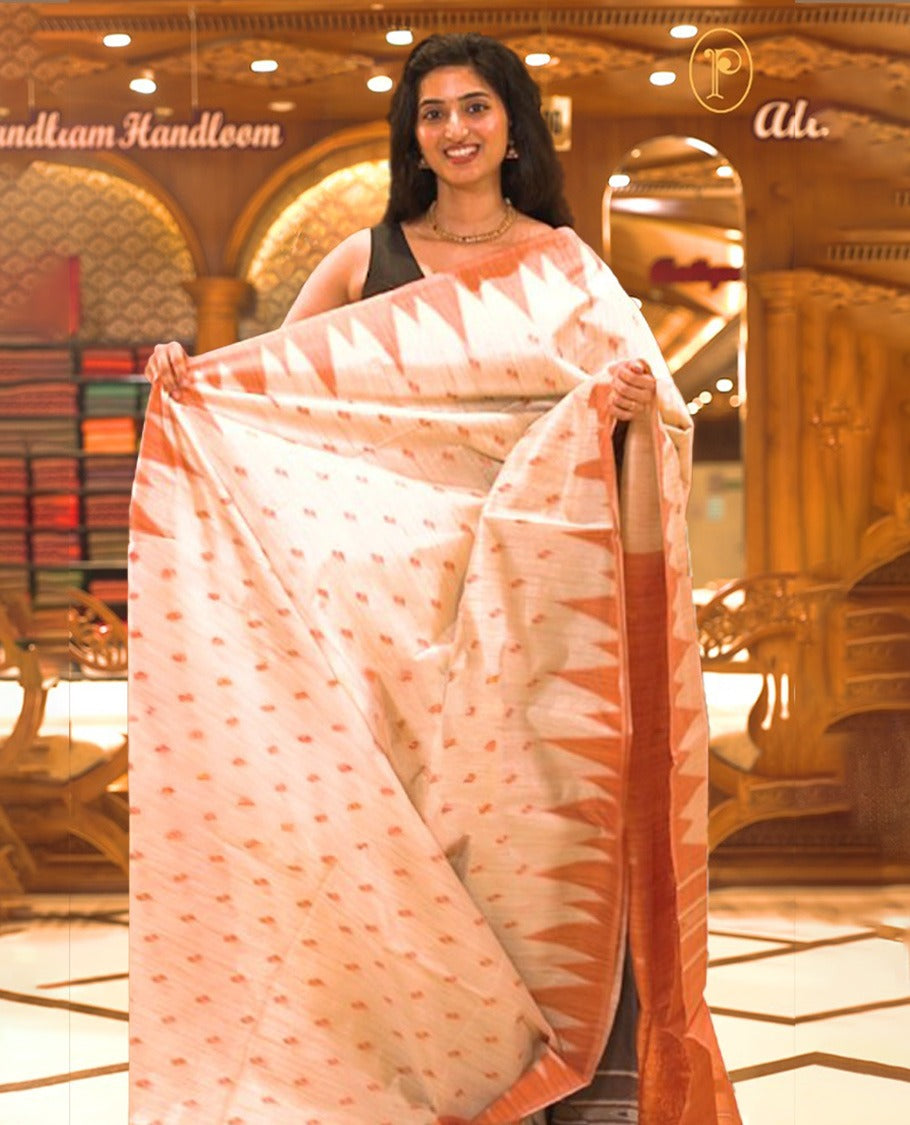 Cream colour Semi Jute saree featuring thread motifs across the body with a rust orange colour traditional temple border, paired with a running blouse piece.