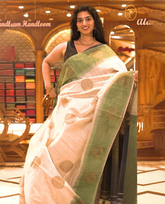 Cream colour Semi Jute saree featuring bold zari motifs across the body with a Green colour parallel panel border, paired with a running blouse piece.