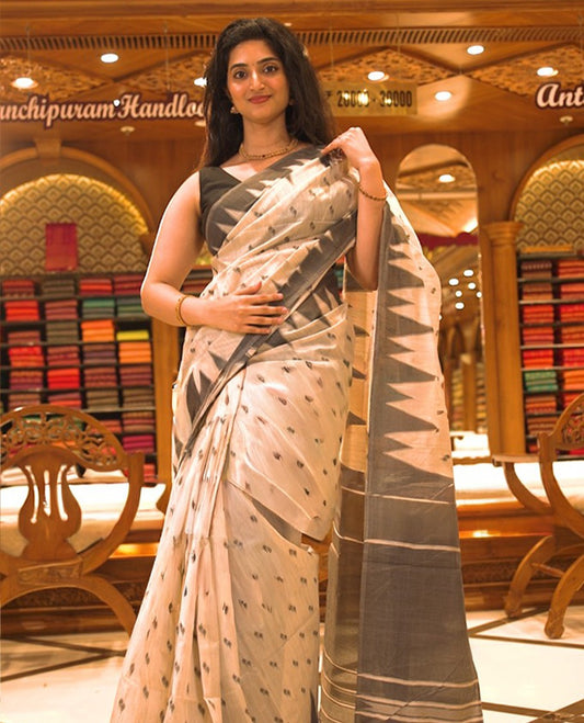Cream colour Semi Jute saree featuring thread motifs across the body with a black colour traditional temple border, paired with a running blouse piece.