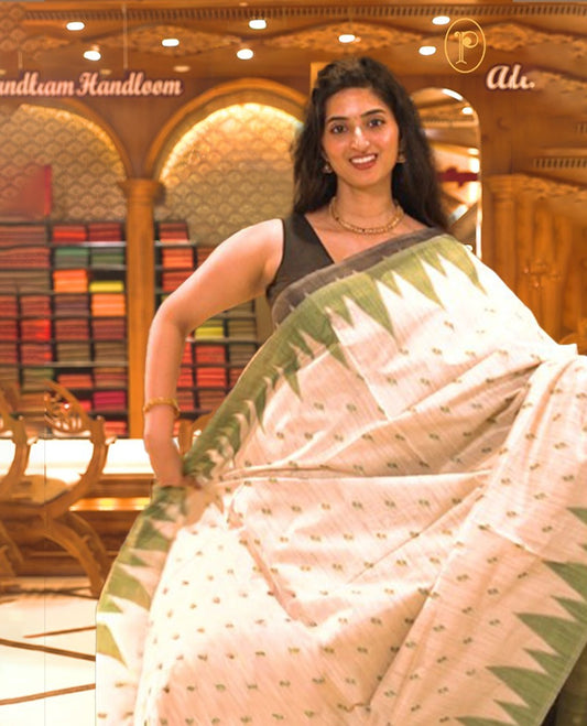 Cream colour Semi Jute saree featuring thread motifs across the body with a Green colour traditional temple border, paired with a running blouse piece.
