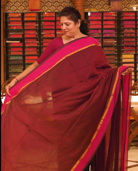 Maroon colour Mul Cotton saree featuring a simple plain body with a contrast border, offering a classic and elegant look. Comes without a blouse piece.