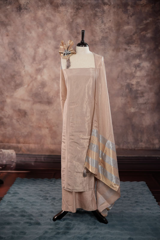 Beige colour Semi Tissue Silk Salwar Material featuring plain body, paired with Santoon bottom and Small Golden line with silver lin detailed Dupatta with tassels.