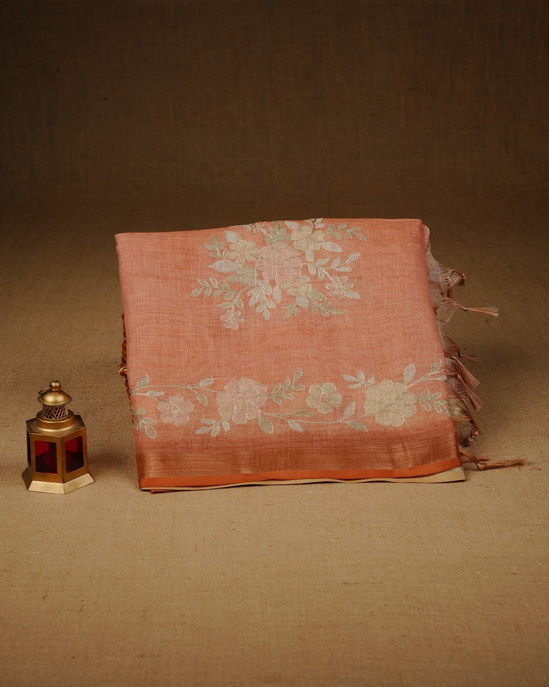 Burnt orange colour linen tissue saree featuring Floral design with Aari work & contrast simple border, comes with matching blouse piece.