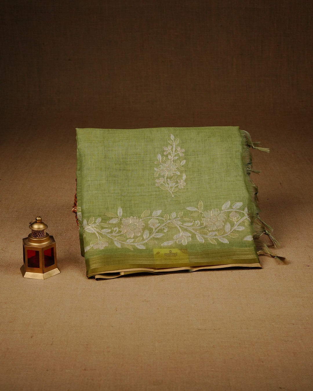 Pista green colour linen tissue saree featuring Floral design with Aari work & contrast simple border, comes with matching blouse piece.