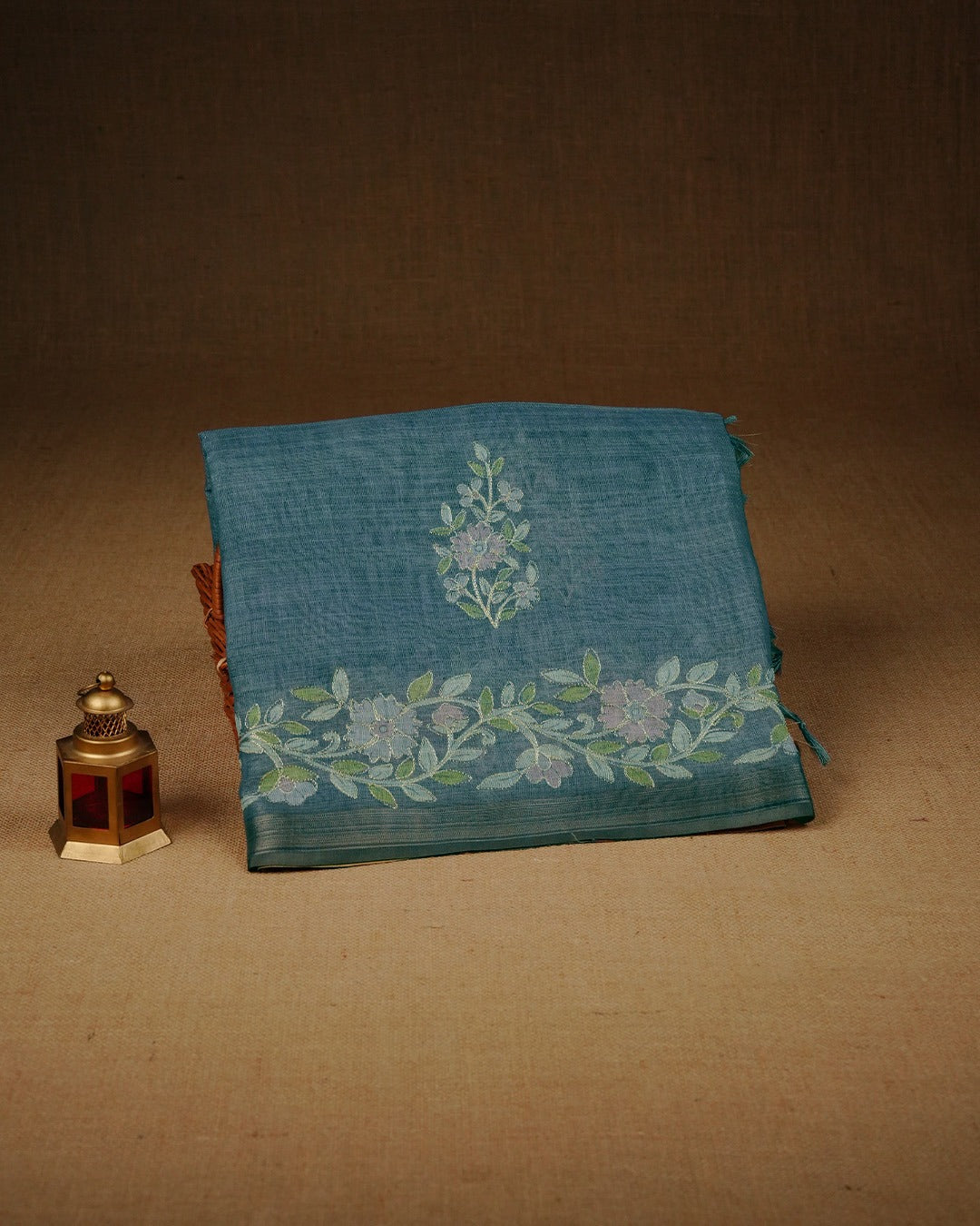 Teal mist colour linen tissue saree featuring Floral design with Aari work & contrast simple border, comes with matching blouse piece.