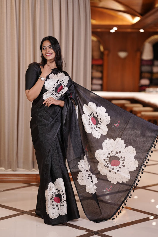 Black colour Semi khadi saree with bold white floral motifs and subtle red accents, exuding timeless elegance and modern charm, paired with a matching blouse.