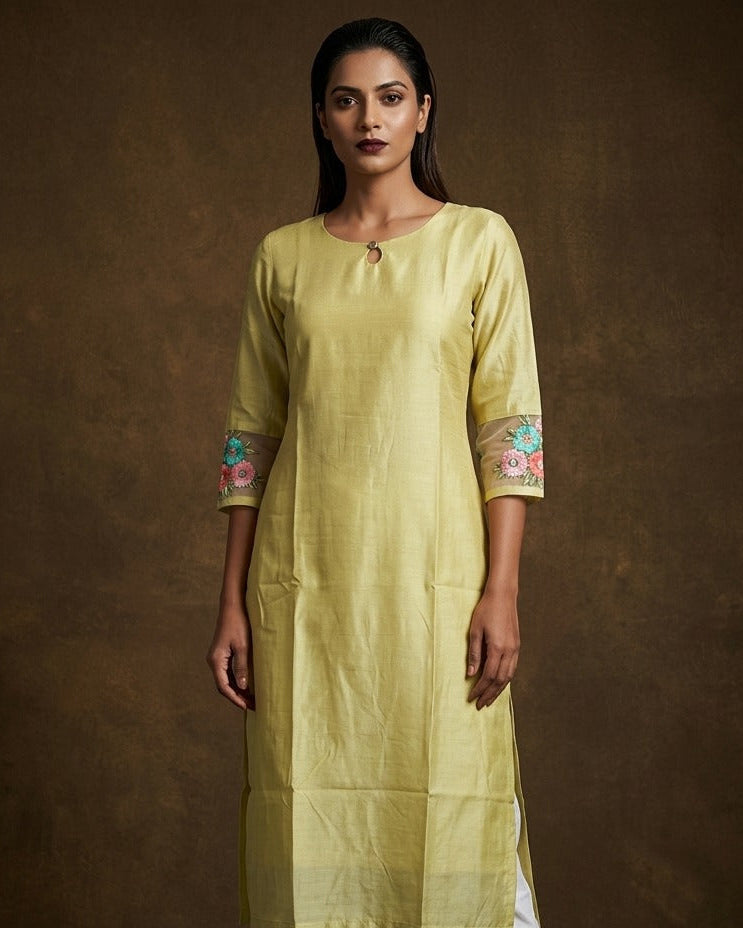 Pistachio green solid kurti featuring a round neckline with a subtle keyhole detail, a straight calf-length silhouette, and three-quarter sleeves highlighted with delicate floral embroidery.